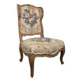 Louis XV style armchair in natural wood with floral upholstery.