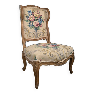 Louis XV style armchair in natural wood with floral upholstery.
