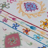 White suzani kilim rug with multi-colored embroidered patterns