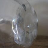 Antique glass carafe with a round belly and floral neck.