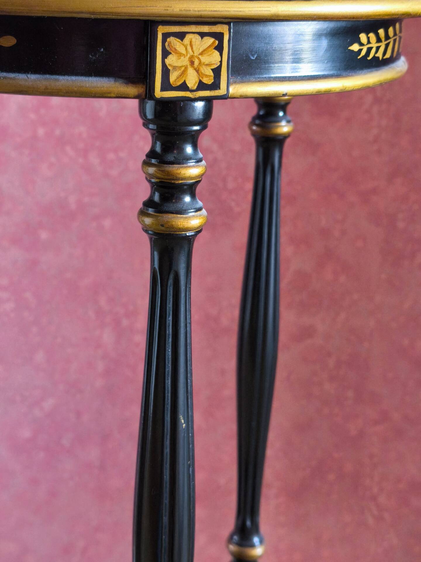 Tripod stool in blackened wood with painted floral decoration.