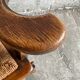 Fauteuil brutaliste en bois massif brun foncé avec assise en rotin naturel et dossier en cuir cognac