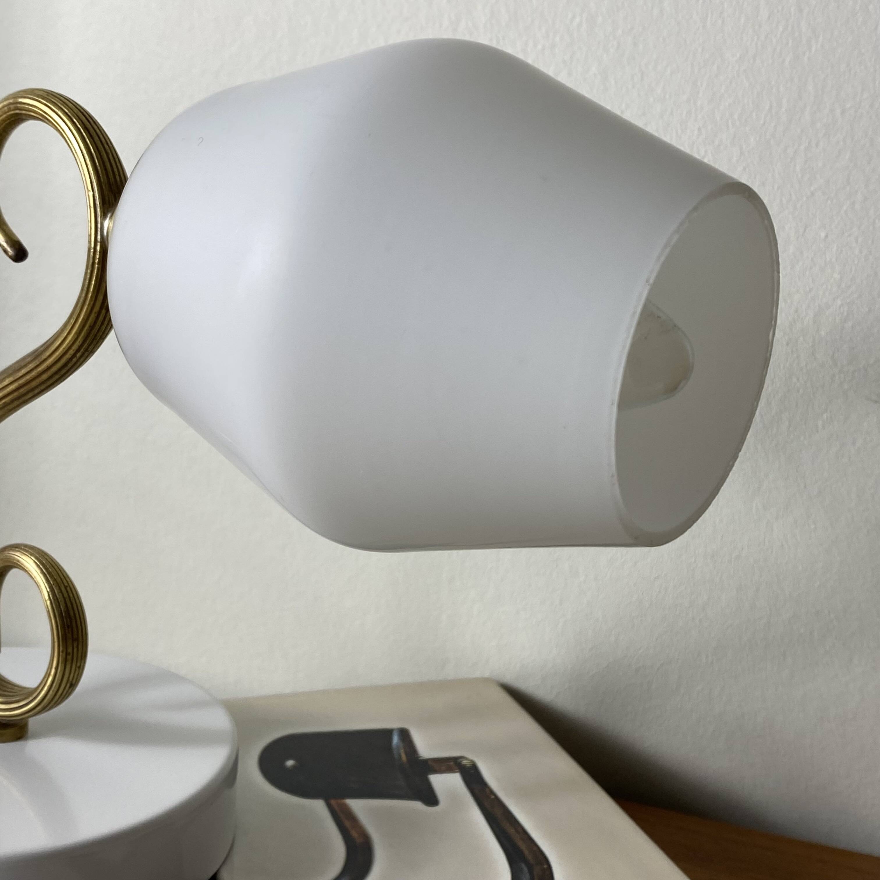 Swan neck wall light in brass with a white glass shade.