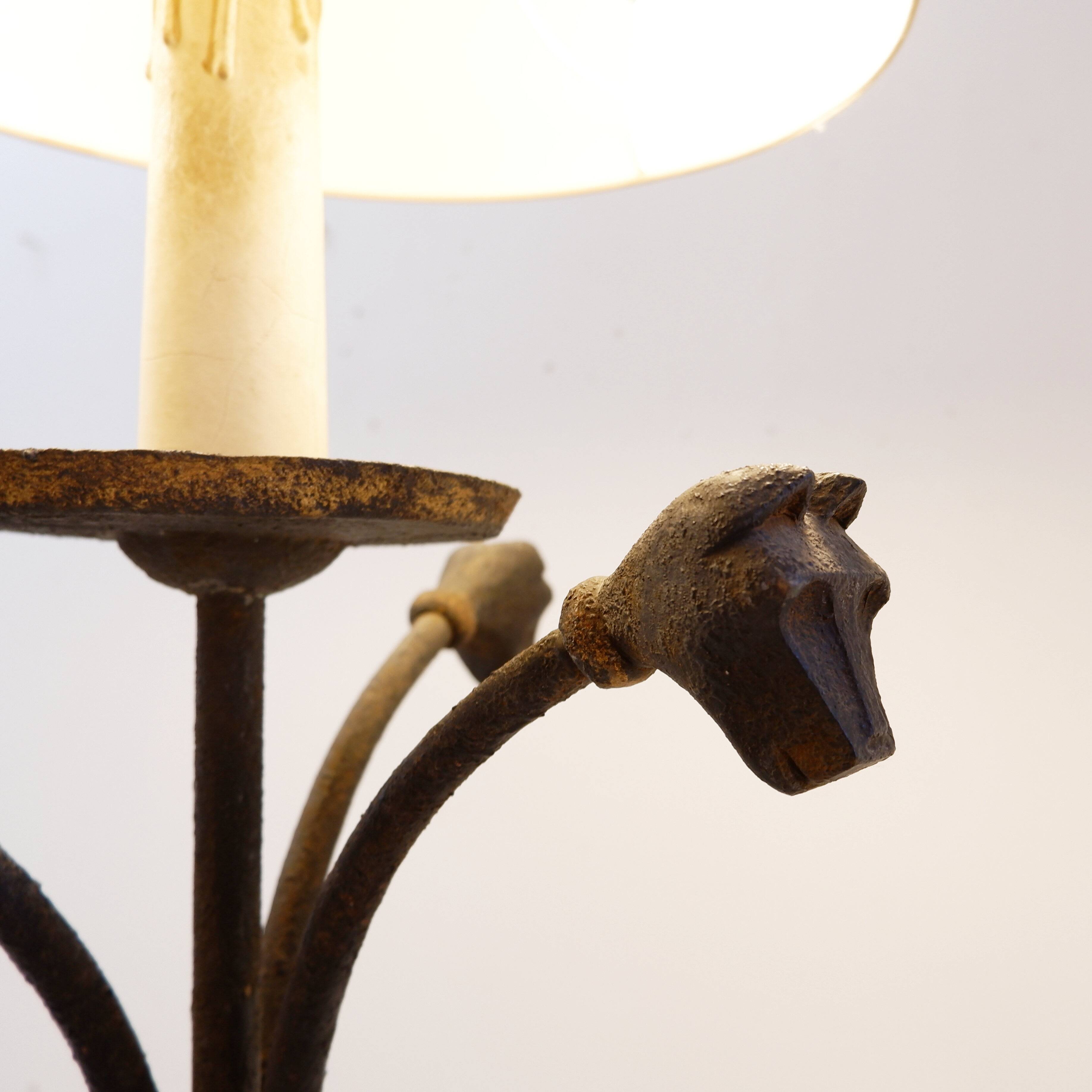 Wrought iron tripod floor lamp decorated with stylized animal heads