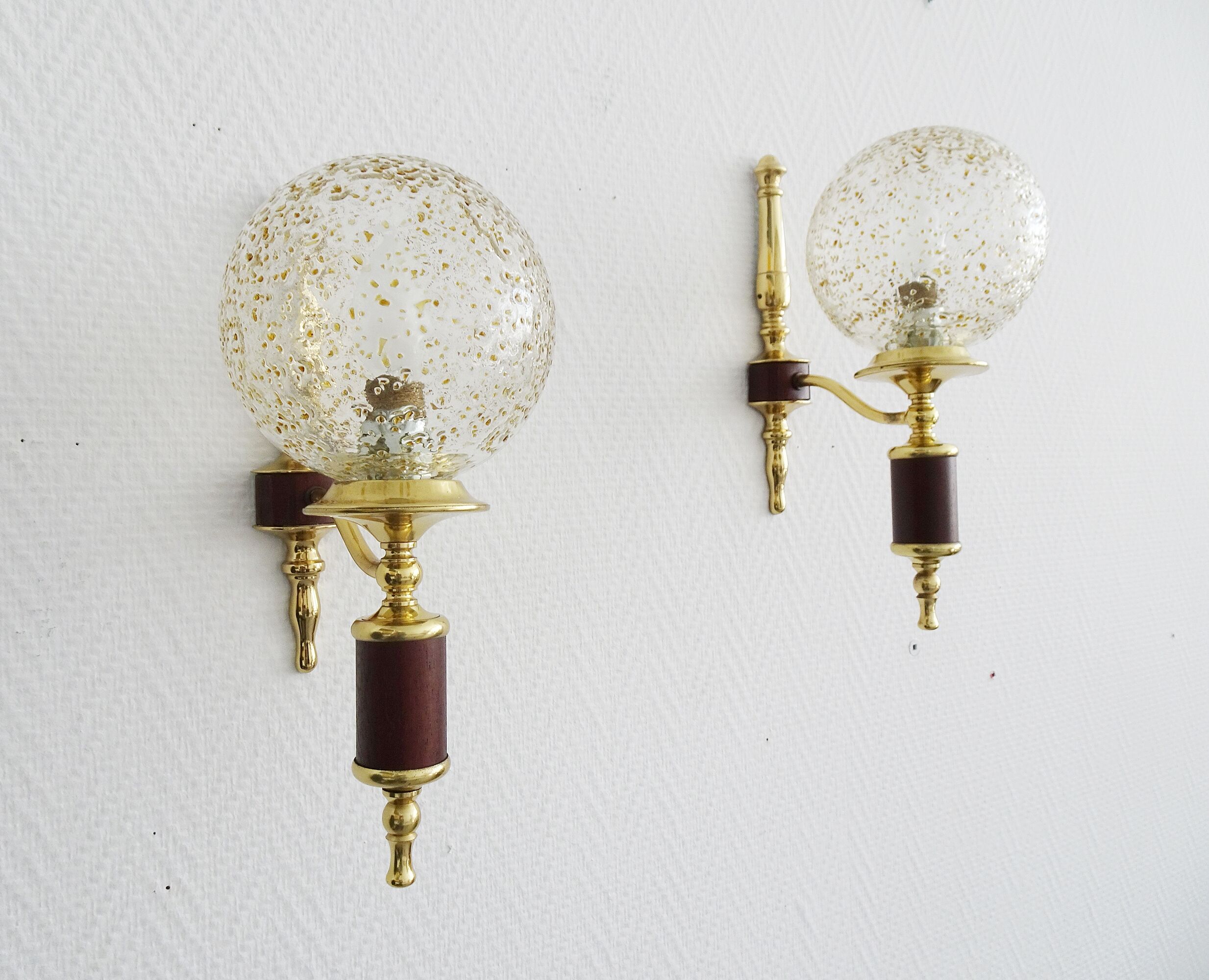Golden wall lamps with round glass shades and teak veneer