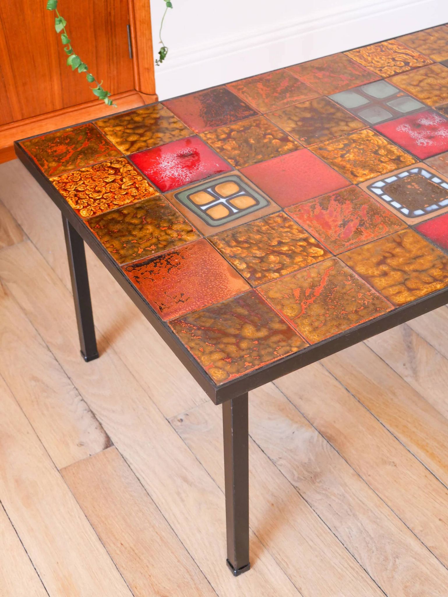 Ceramic and black iron coffee table, attributed to the Roche-Bobois brand, with a black metal base and structure, rectangular ceramic top from Vallauris with colourful patterns in ochre and orange, design from the 1970s.