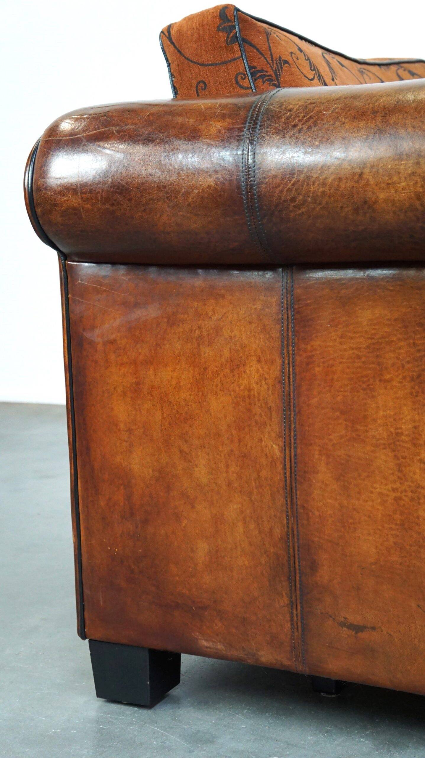 Canapé en cuir de mouton 2,5 places, luxueux et confortable, avec des coussins en tissu.