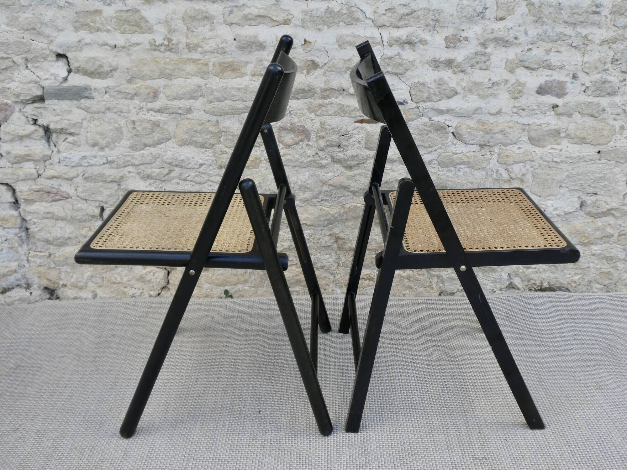 Paire de chaises pliantes en bois noirci et assise cannée
