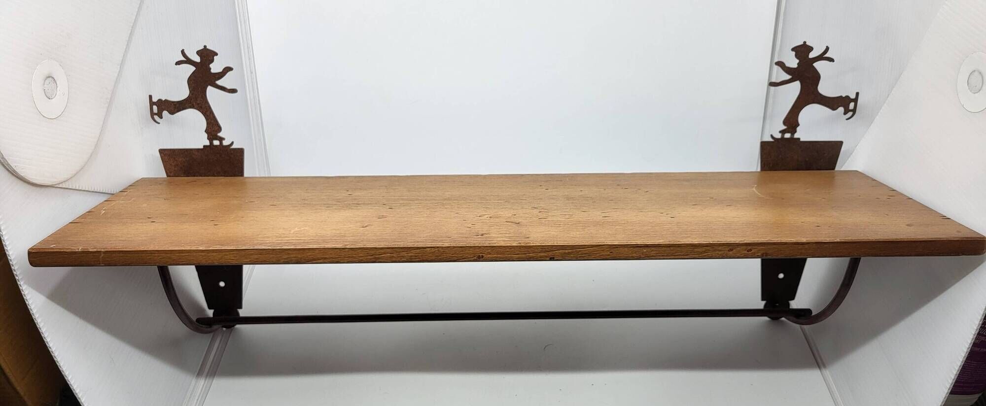 Wall shelf in wood and metal with a decoration of ice skaters.