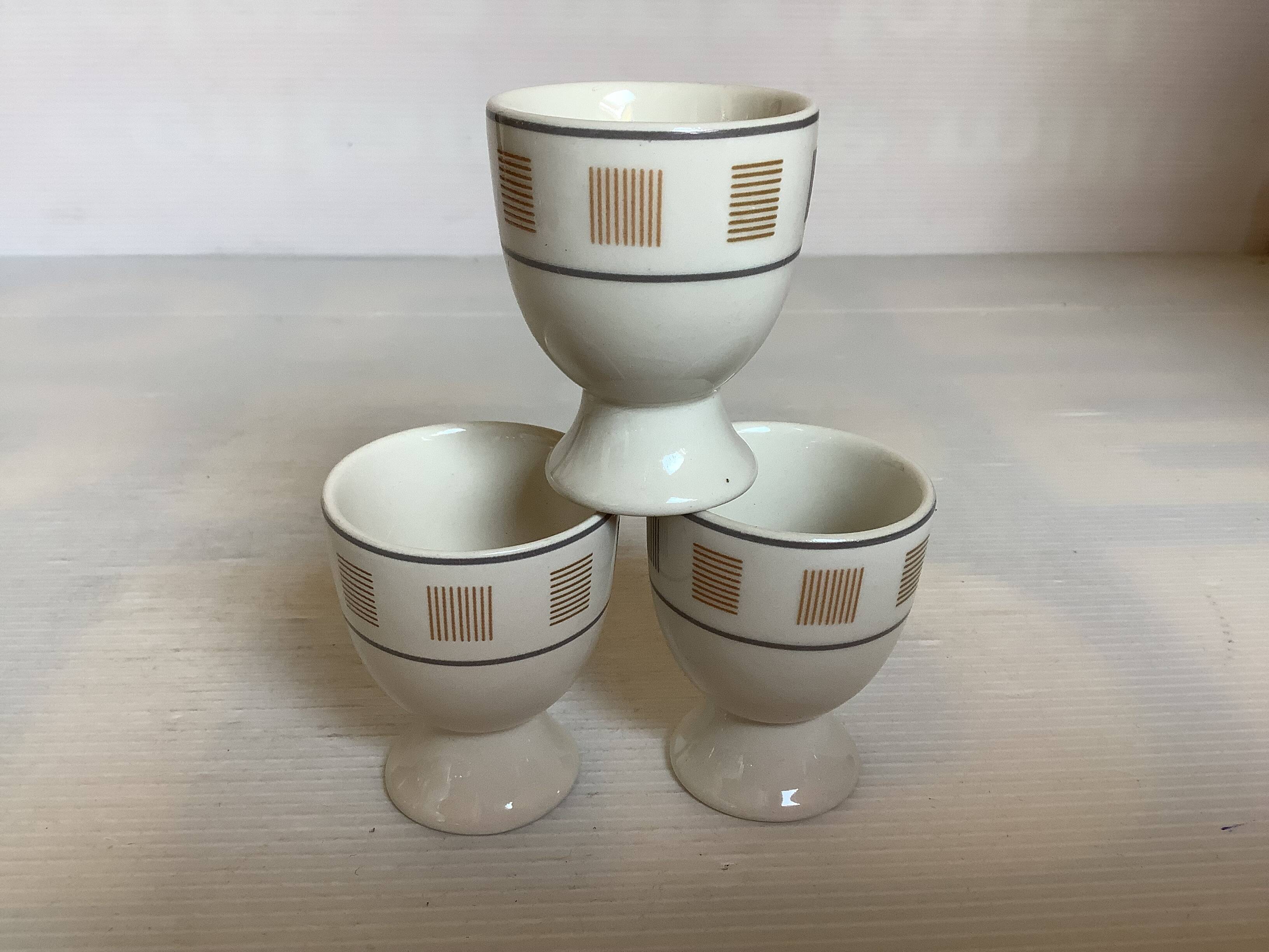 Three egg cups with geometric patterns in beige and brown.