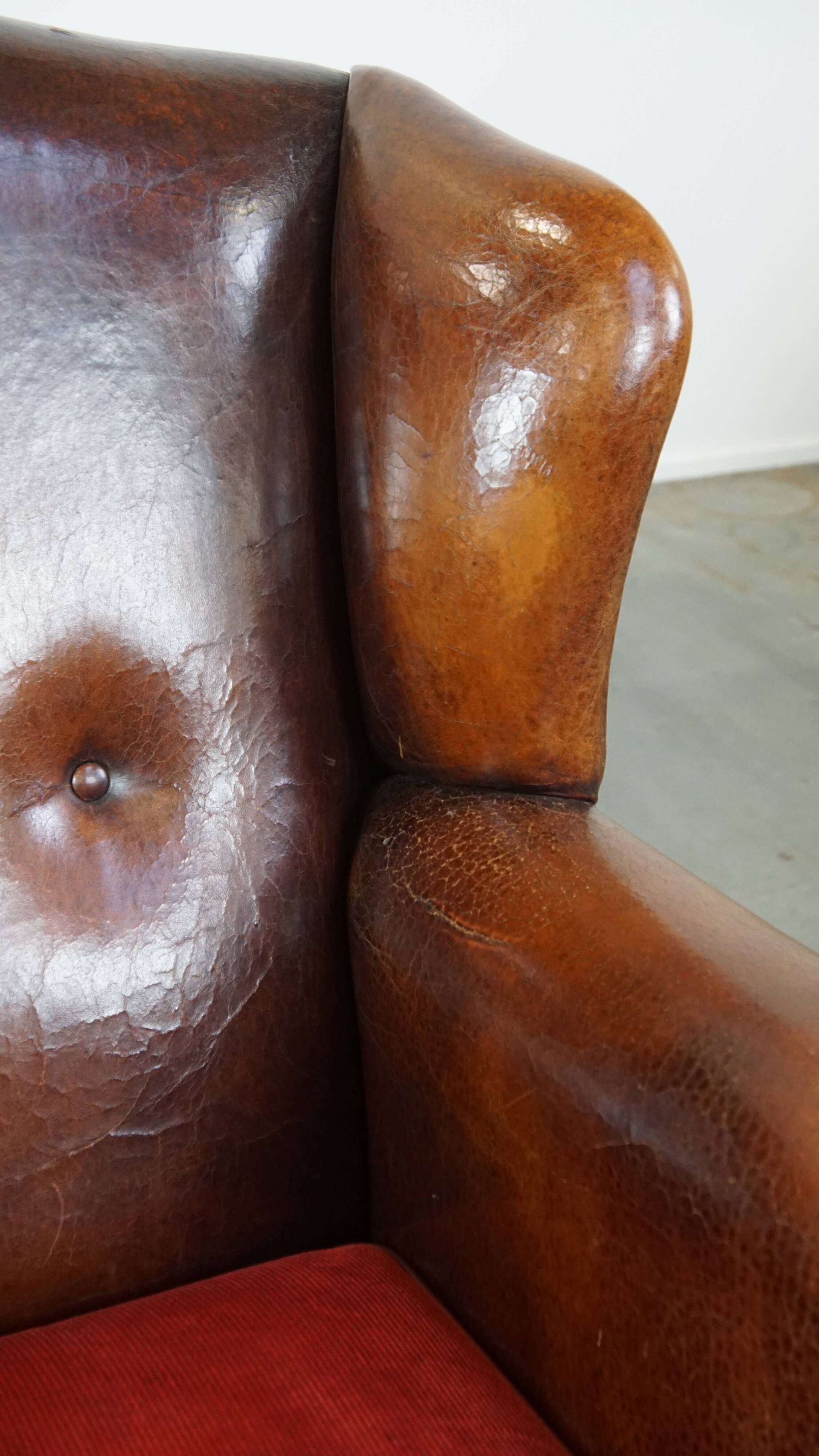 Sheepskin leather wingback chair with a red corduroy seat cushion