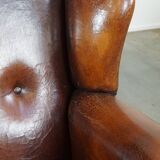 Sheepskin leather wingback chair with a red corduroy seat cushion