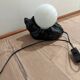 Black cat playing with its globe table lamp