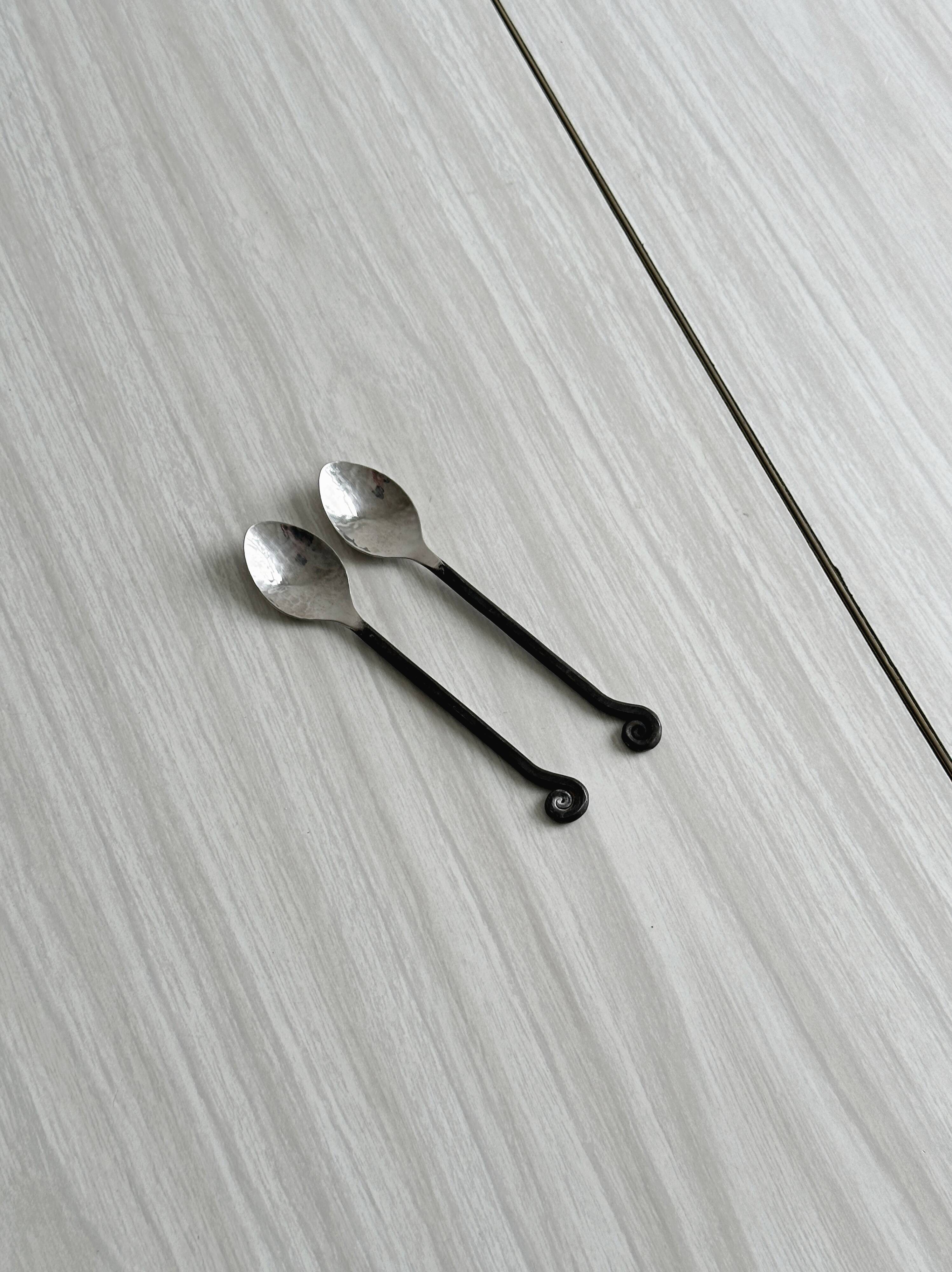 Two small hammered metal teaspoons with a snail pattern.