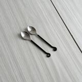 Two small hammered metal teaspoons with a snail pattern.