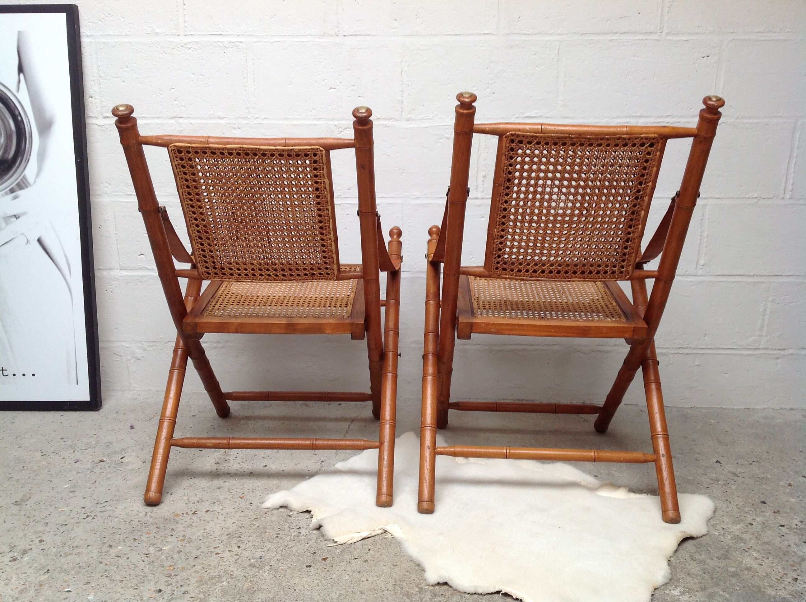Pair of folding chairs in bamboo and caning, leather and brass