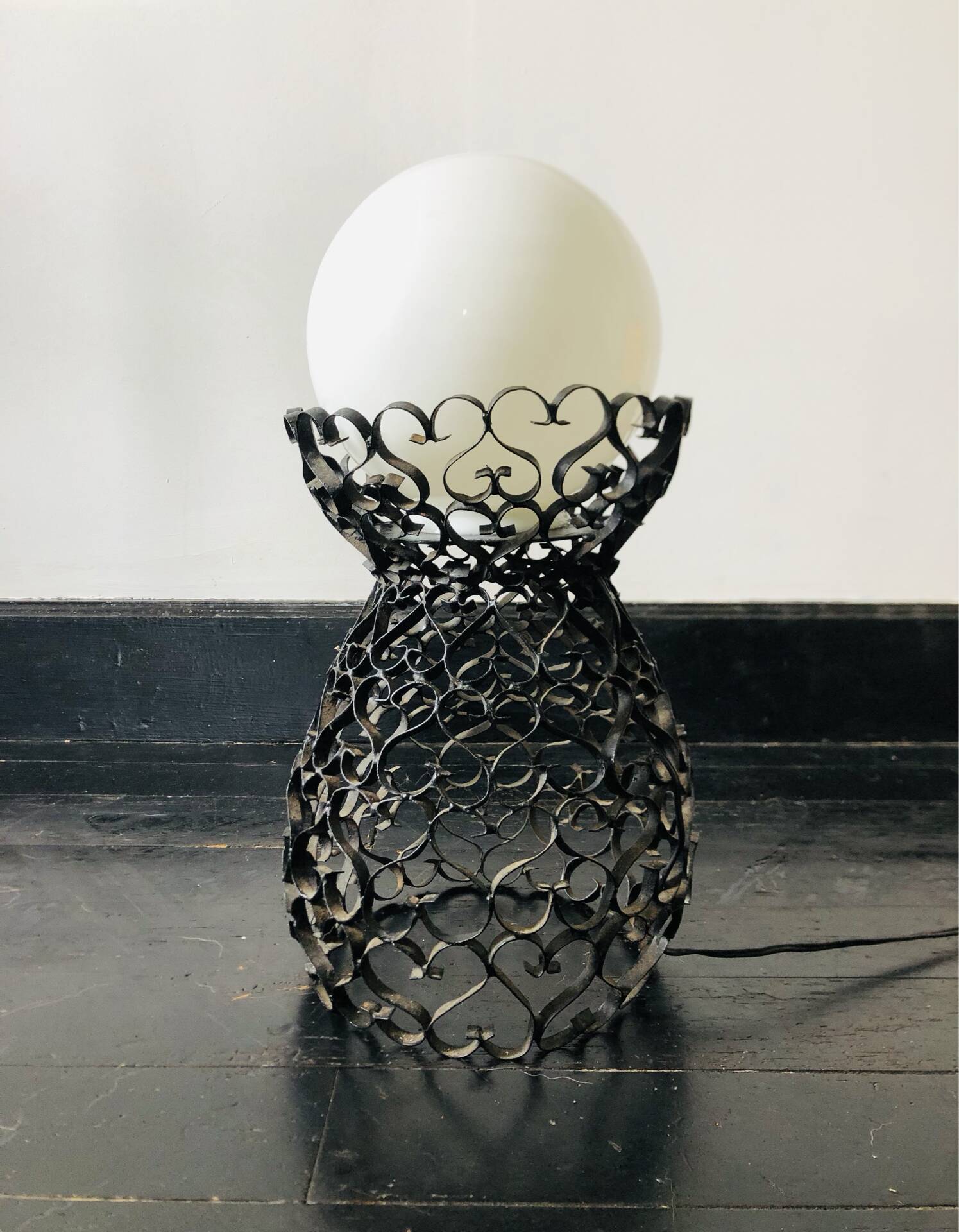 Handcrafted wrought iron lamp with a white opaline globe.