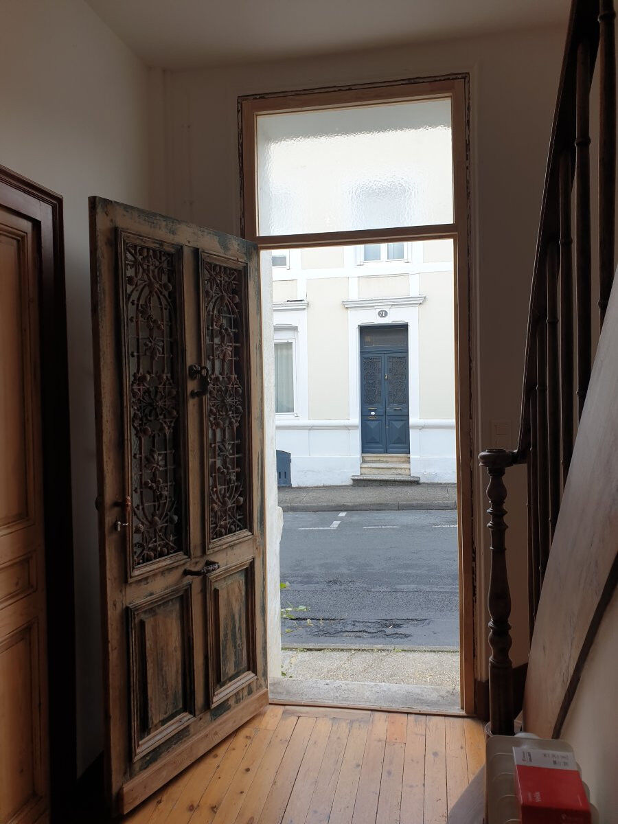 Front door of a house or building in the city centre, with a dolphin door knocker and frame + transom.