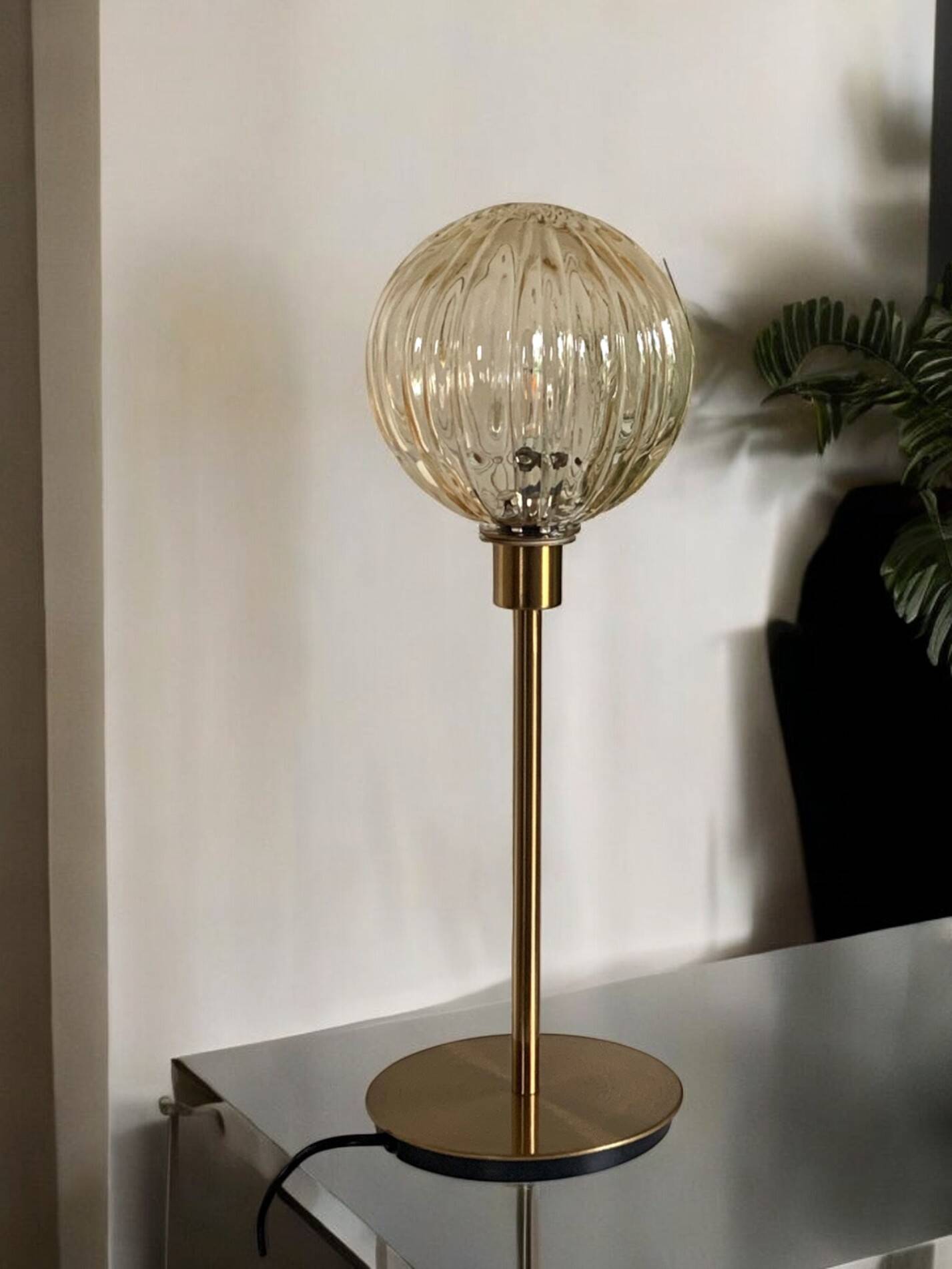 Table lamp with a golden striated globe and a golden base