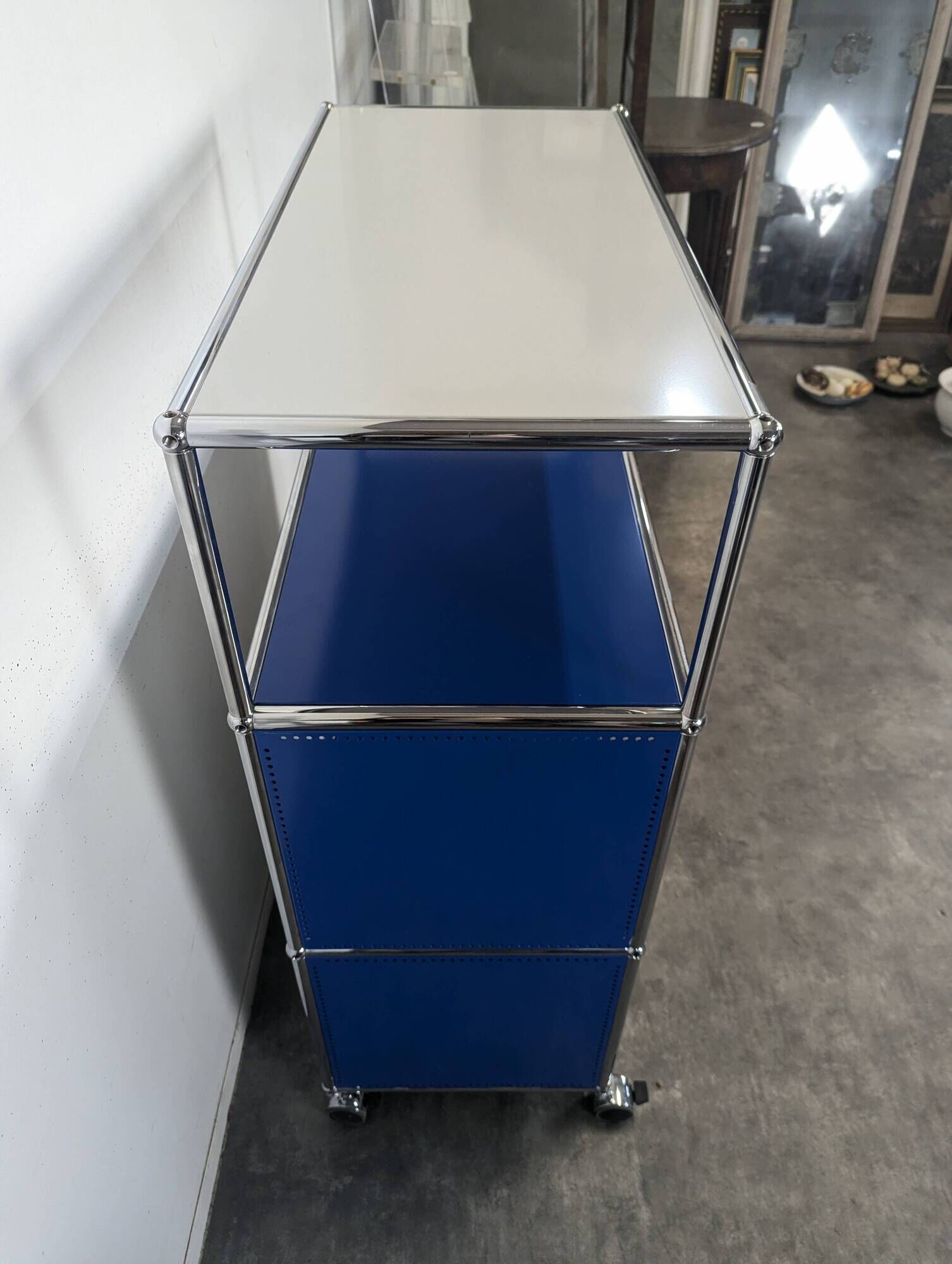 USM Haller furniture in gentian blue and white with a drop-down door on wheels.