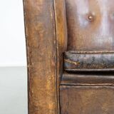 Fauteuil ancien en cuir de mouton sur roulettes et patiné