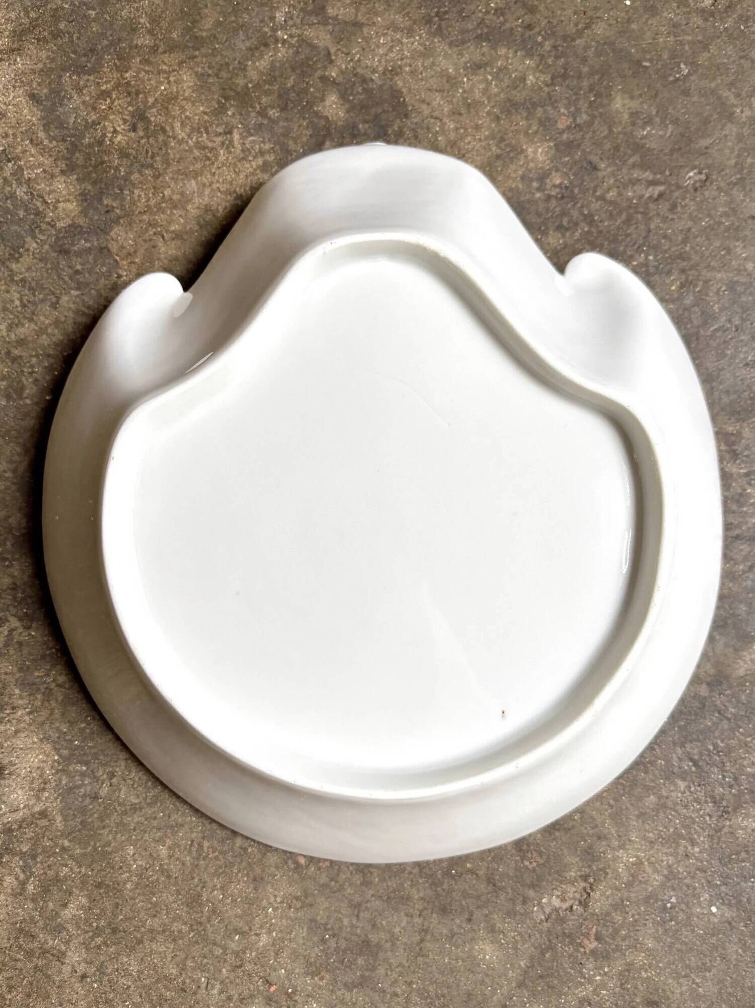Small, shallow porcelain dish shaped like a seashell