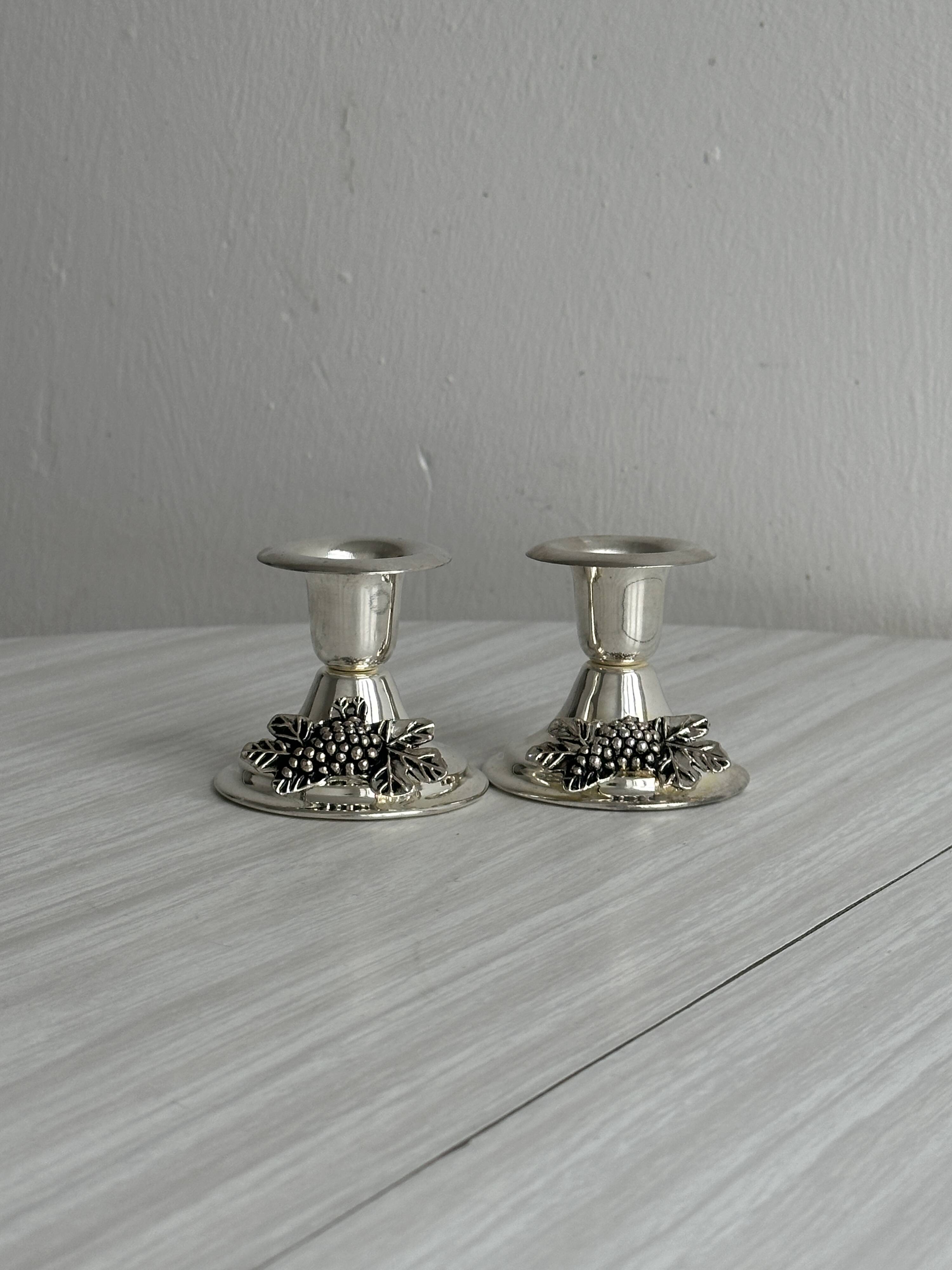 Pair of vintage metal candlesticks with a grape pattern.