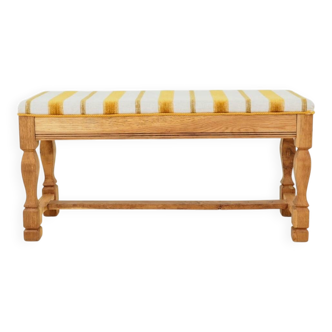 Vintage oak bench with striped linen fabric in a country style.