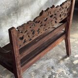 Small antique Indonesian bench in carved teak with plant and floral motifs.