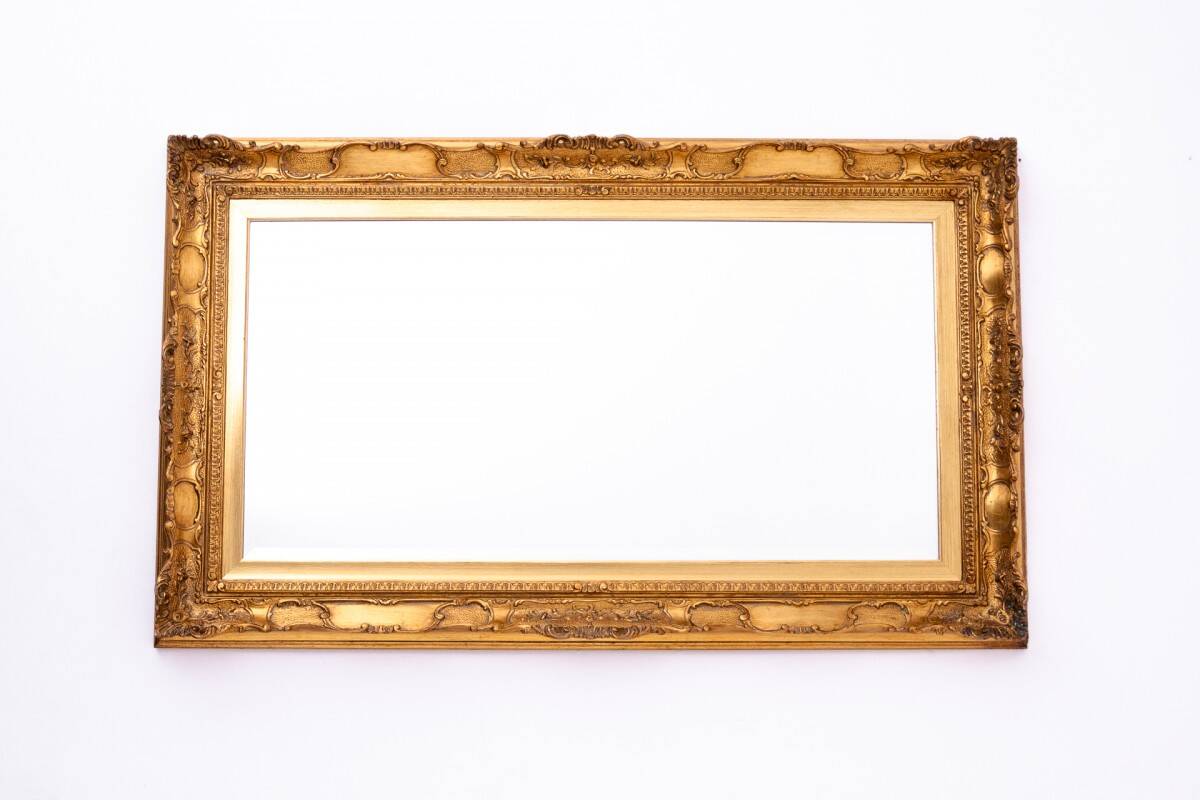 A mirror with a golden, richly carved frame.
