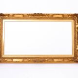 A mirror with a golden, richly carved frame.