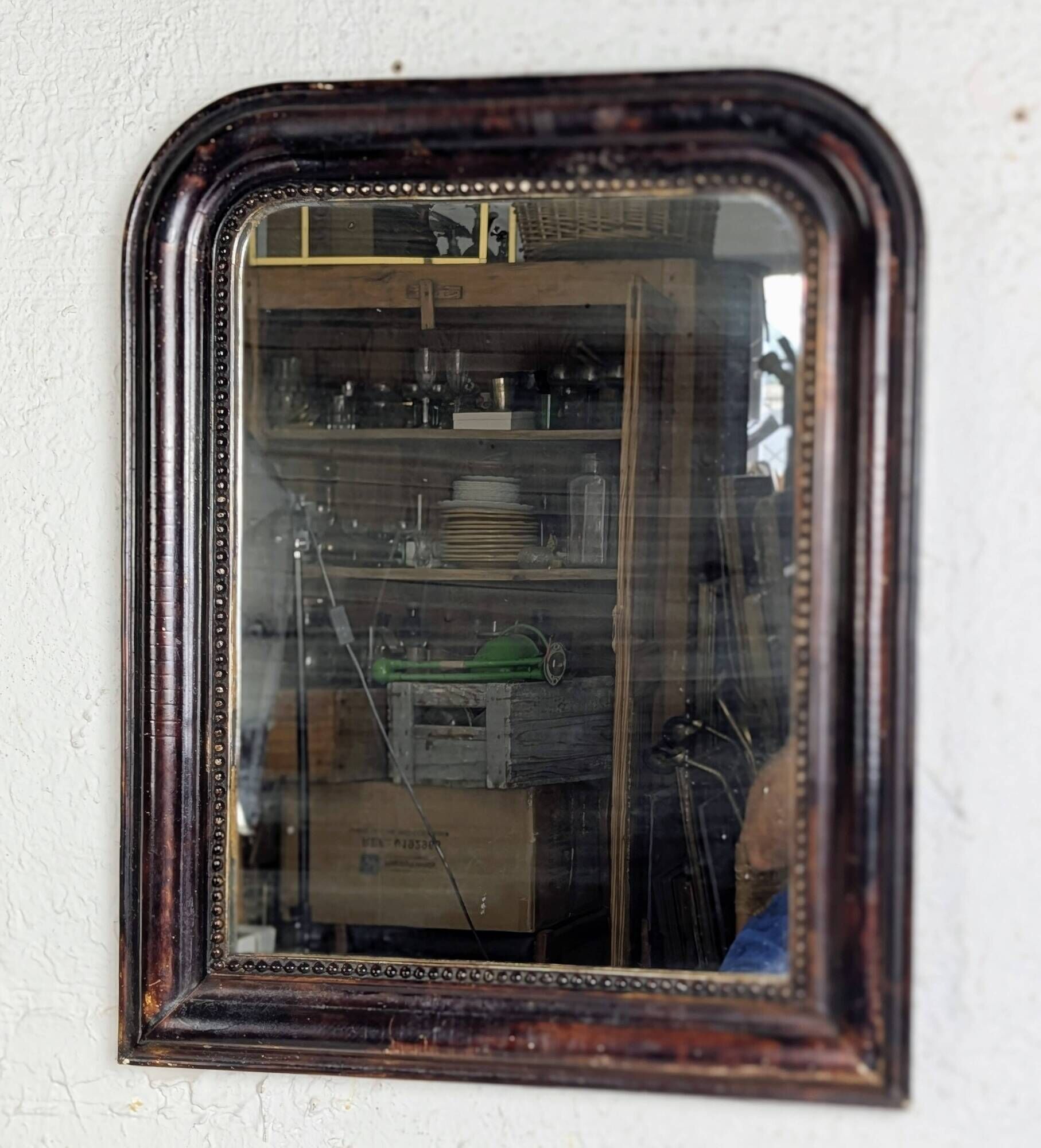 Antique Louis Philippe mirror with a patinated black frame.