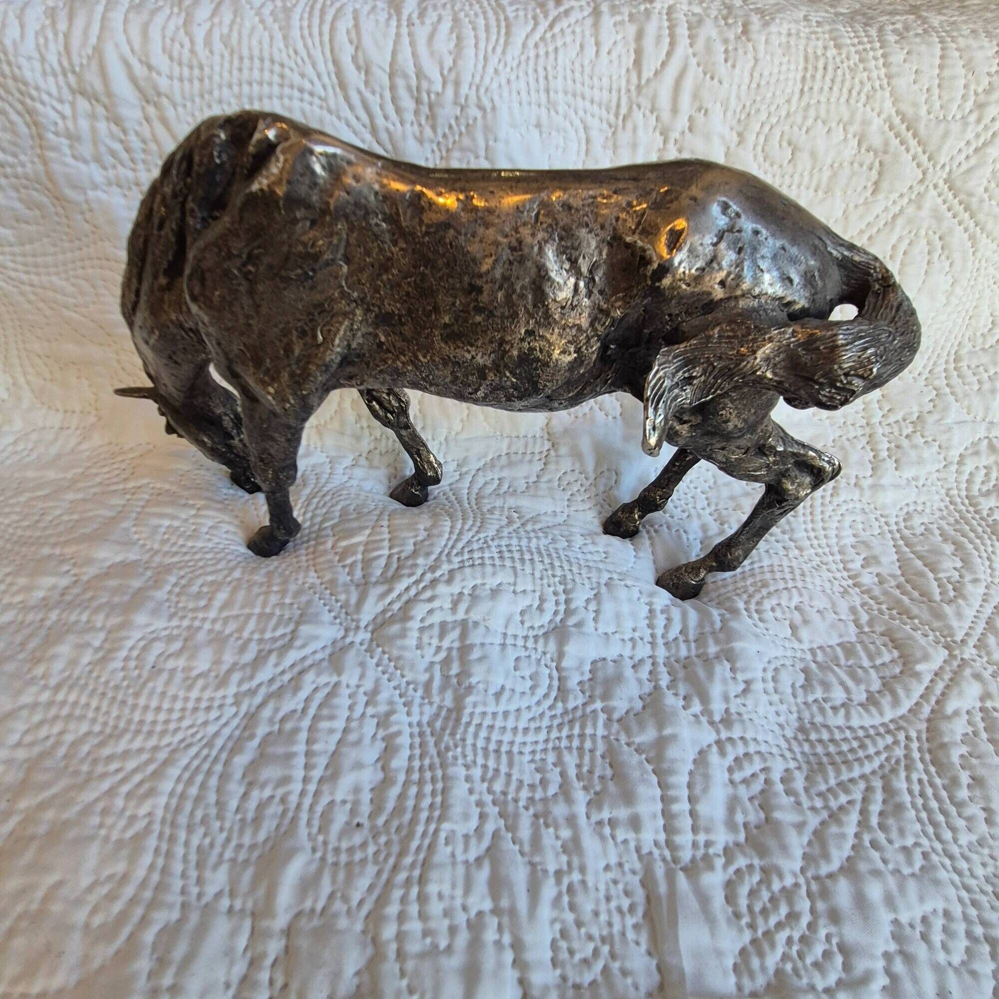 Sculpture of a grazing horse with a silver finish.