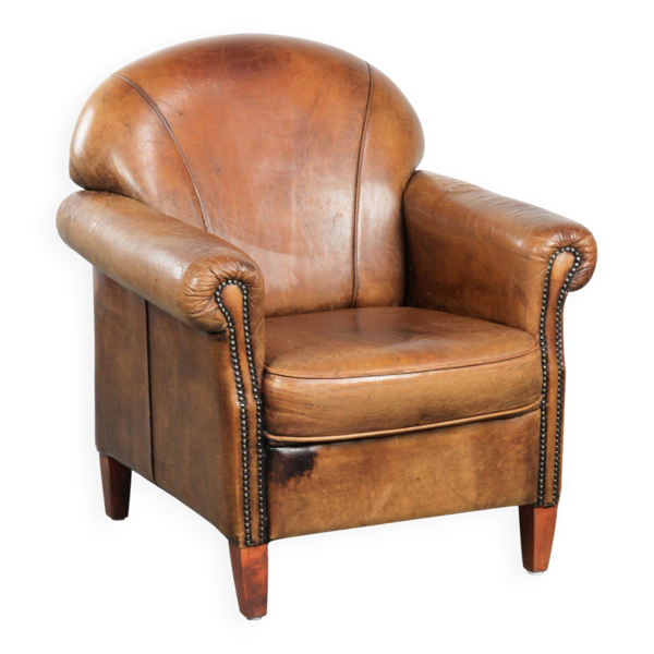 Fauteuil en peau de mouton avec un beau look vintage et une finition cloutée décorative.