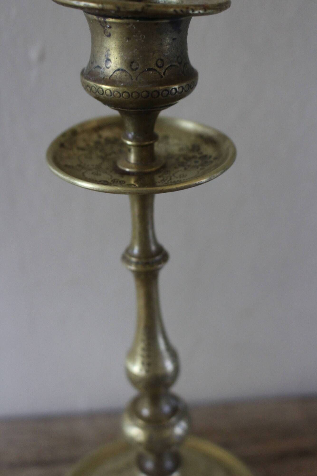 Brass candle holder with flowers and round shape.