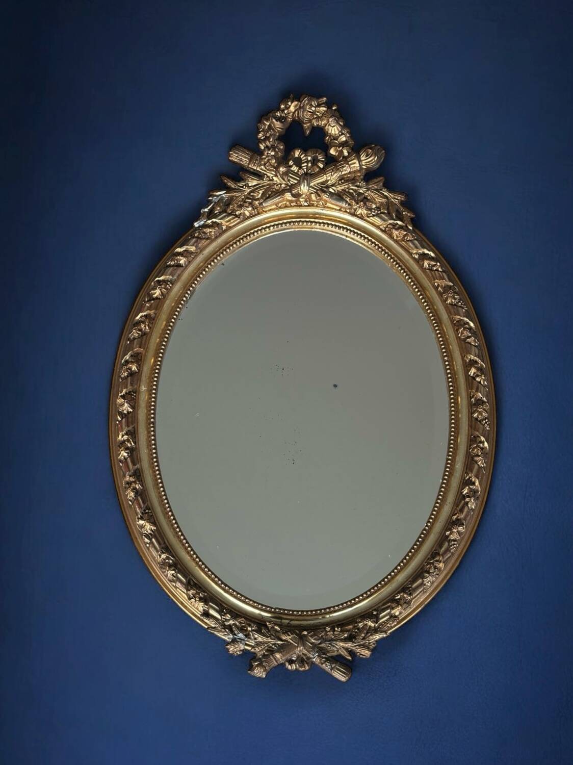 19th century oval gilded mirror, torch & quiver 106cm