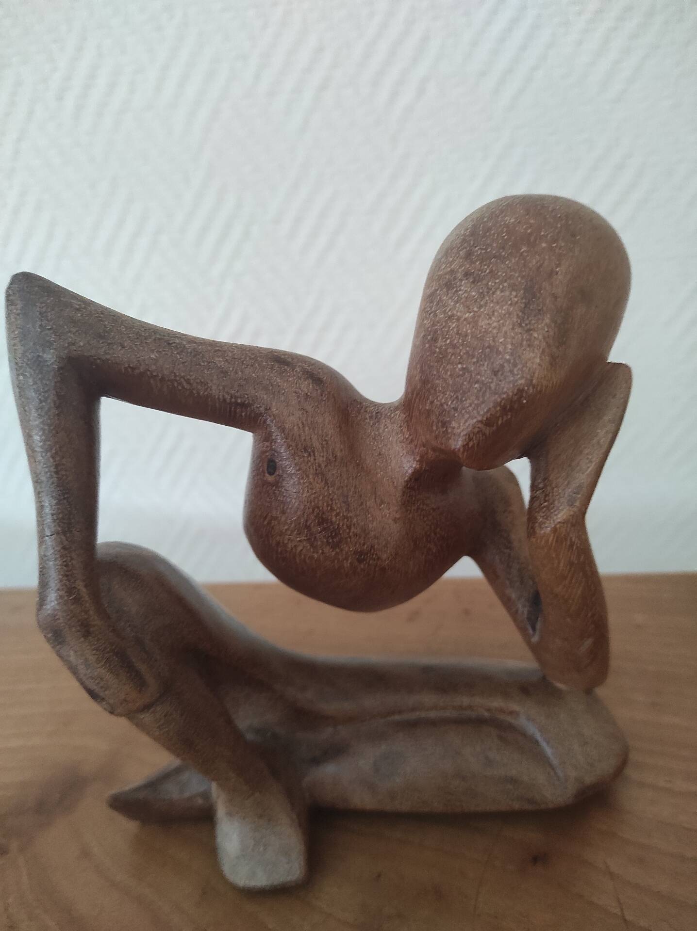 Wooden sculpted statuette of a woman in a pensive pose.
