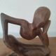 Wooden sculpted statuette of a woman in a pensive pose.