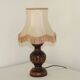 Mid-century French table lamp made of turned carved wood with a fringed shade.