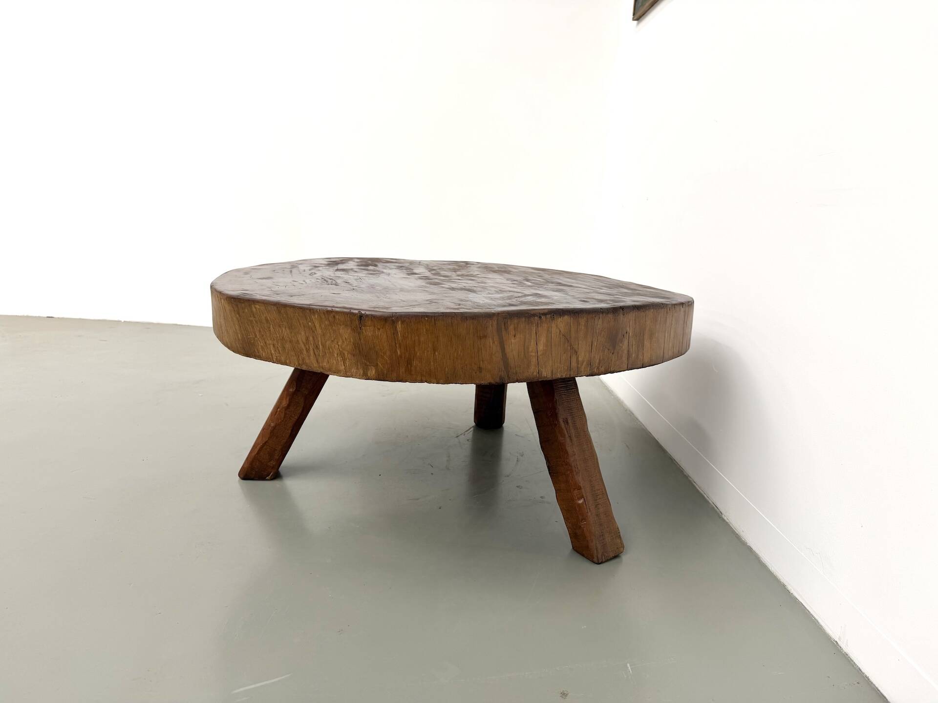 Brutalist coffee table in solid teak, monolithic slab, tripod base.