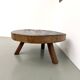 Brutalist coffee table in solid teak, monolithic slab, tripod base.