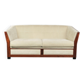 Canapé de style Art Déco avec de magnifiques boiseries et un revêtement en tissu crème.