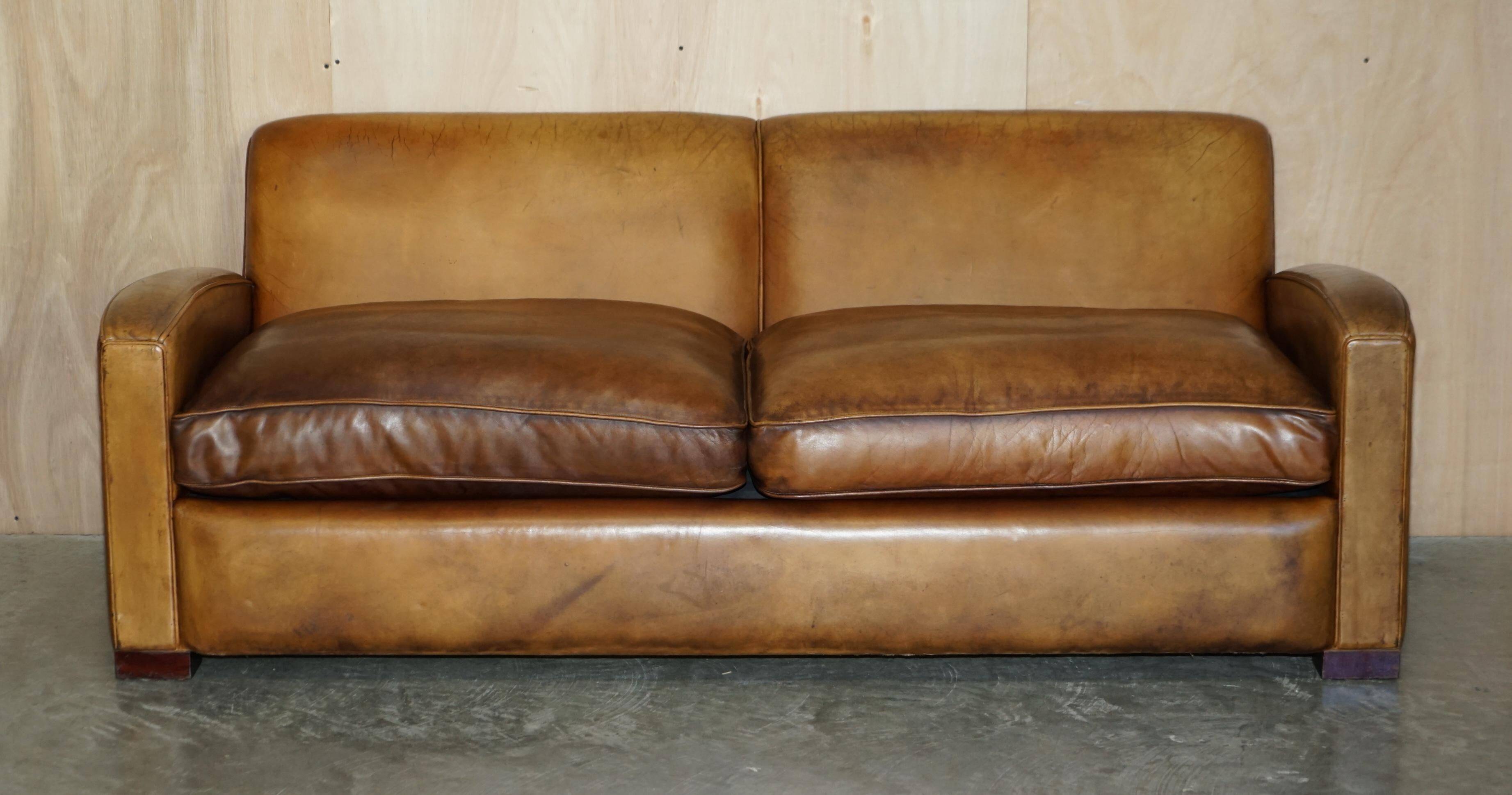 Three-seater Art Deco style leather sofa with feather cushions.