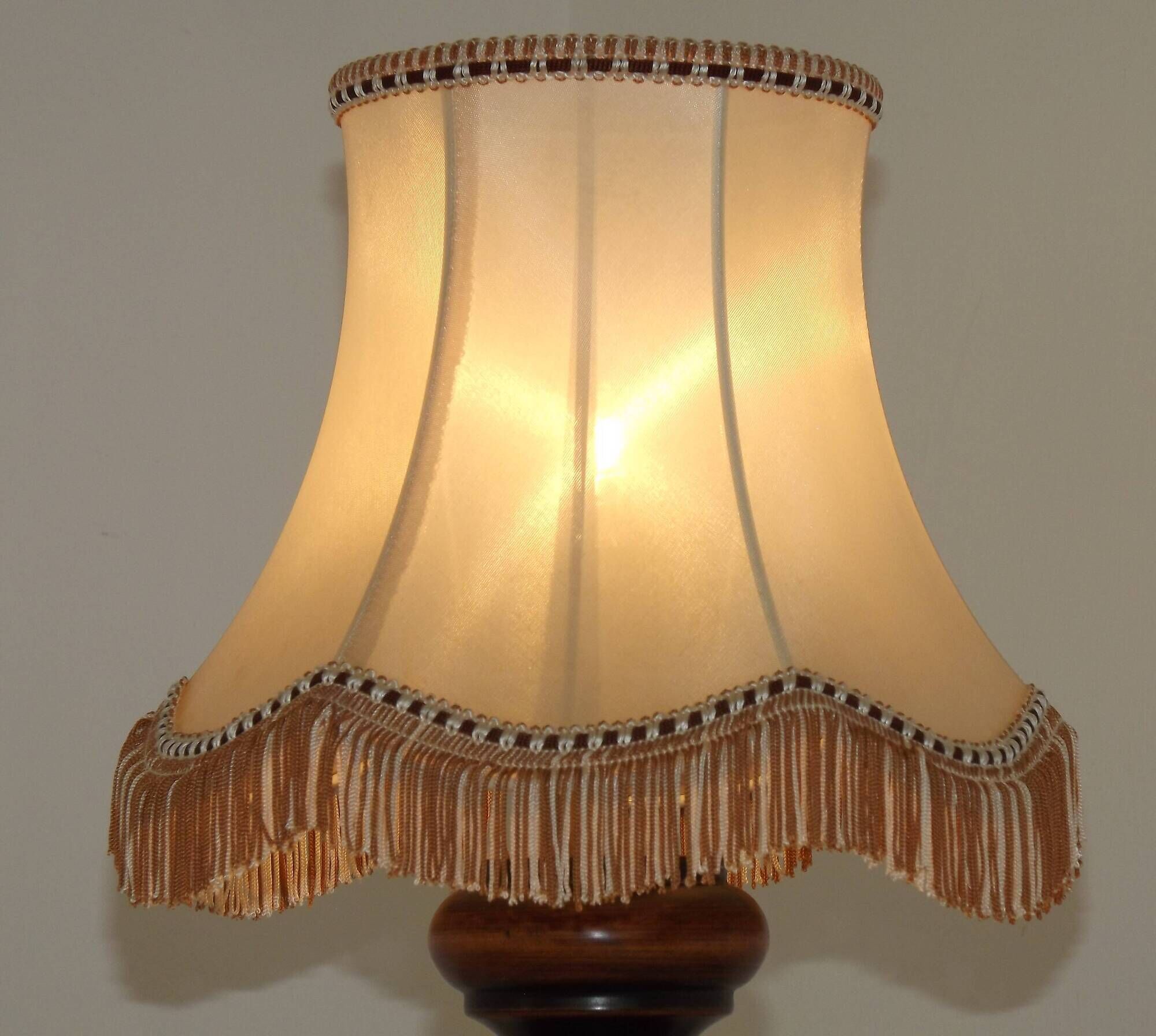 Mid-century French table lamp made of turned carved wood with a fringed shade.
