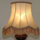 Mid-century French table lamp made of turned carved wood with a fringed shade.