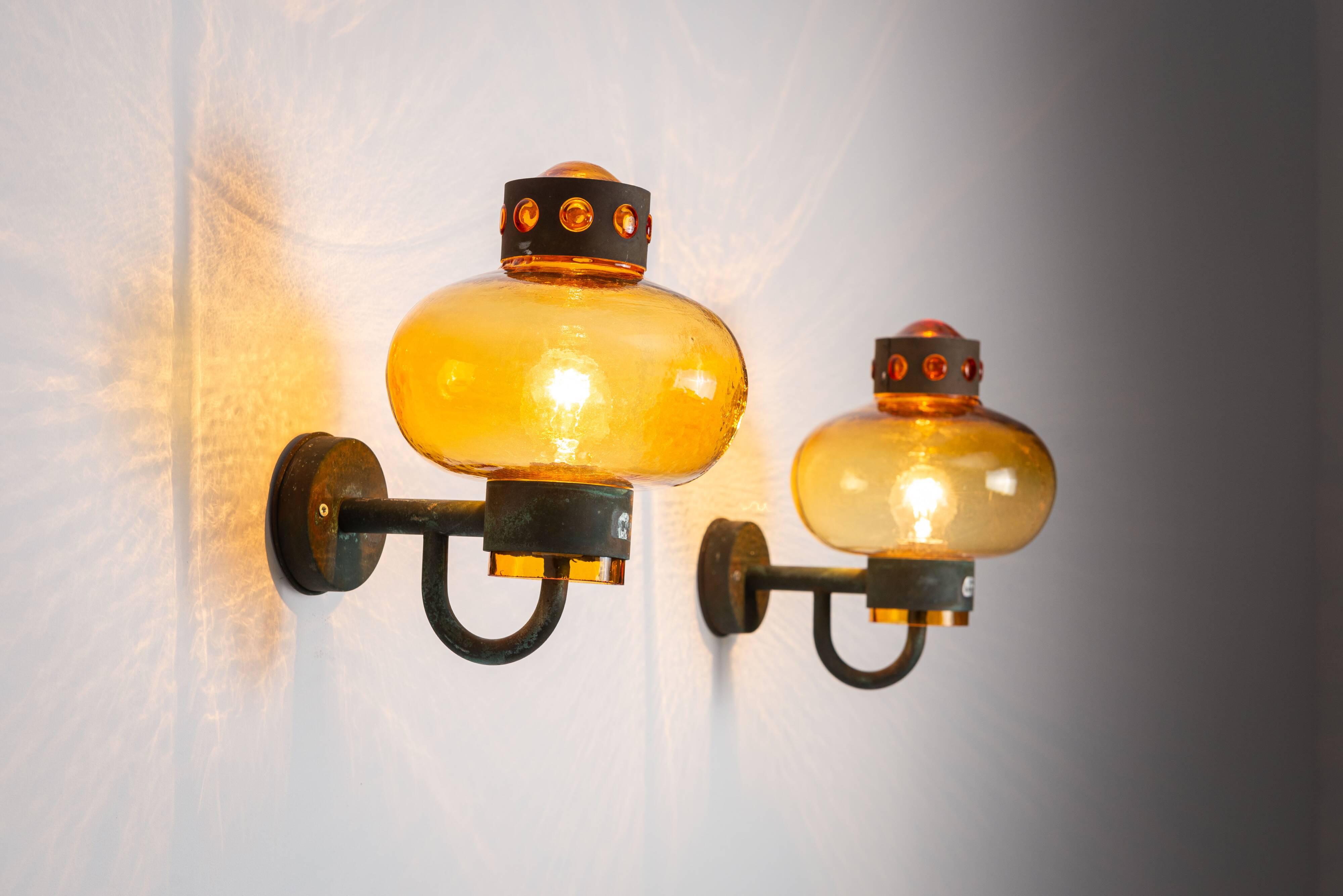 Pair of brass wall lamps with decorated amber coloured shades