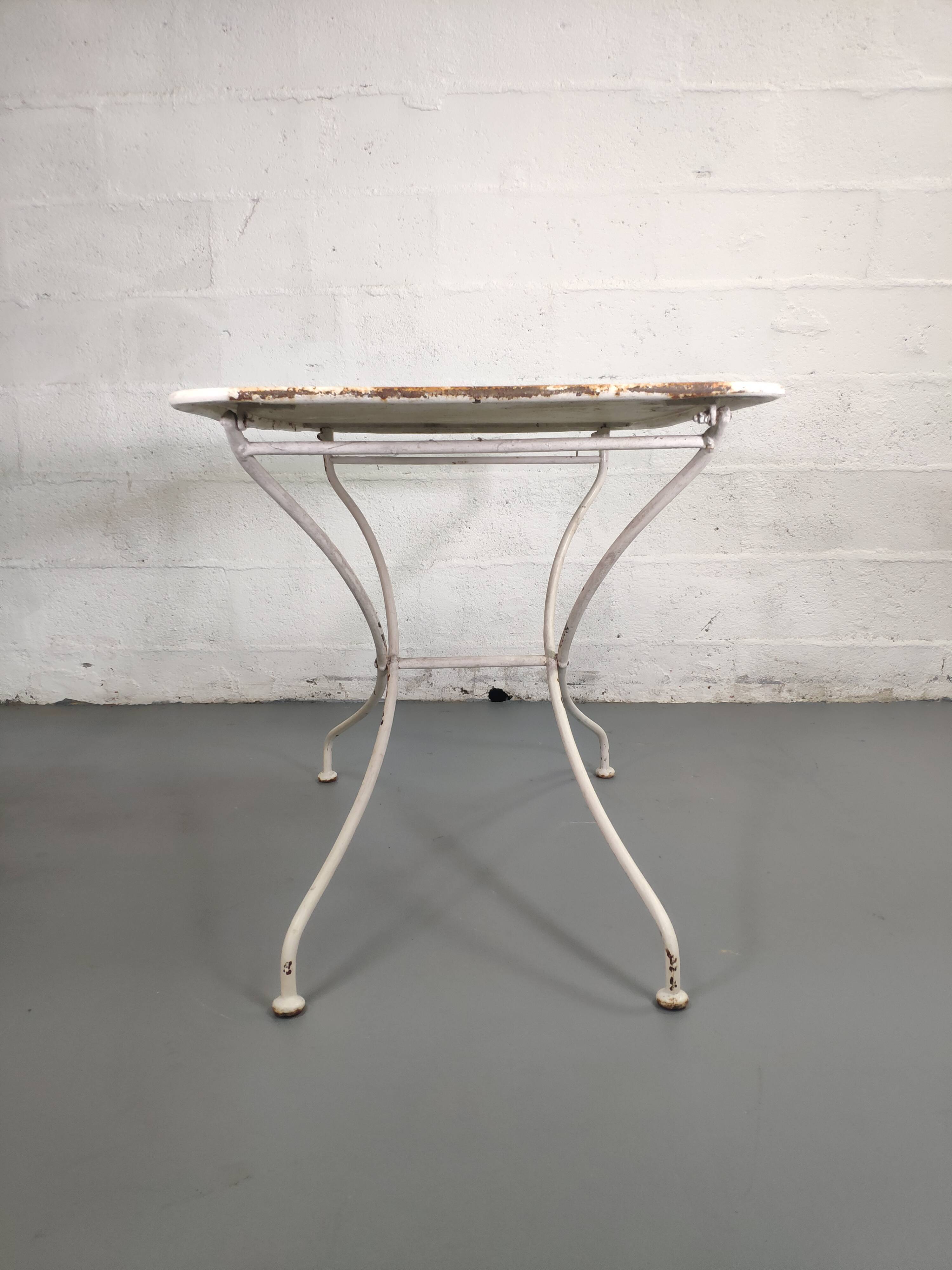 Old folding garden table in white wrought iron