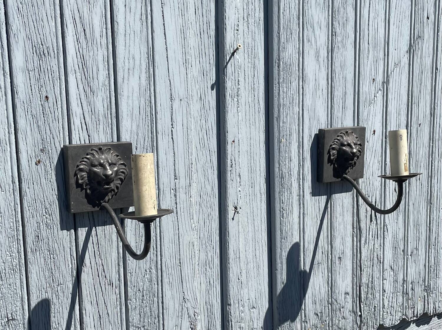 Two lion head wall sconces in tin.