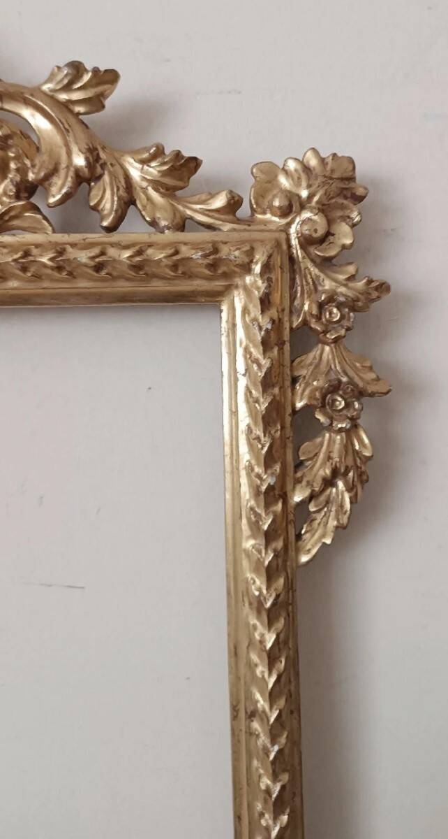 Mirror with a carved wooden frame in an antique style in pure gold.