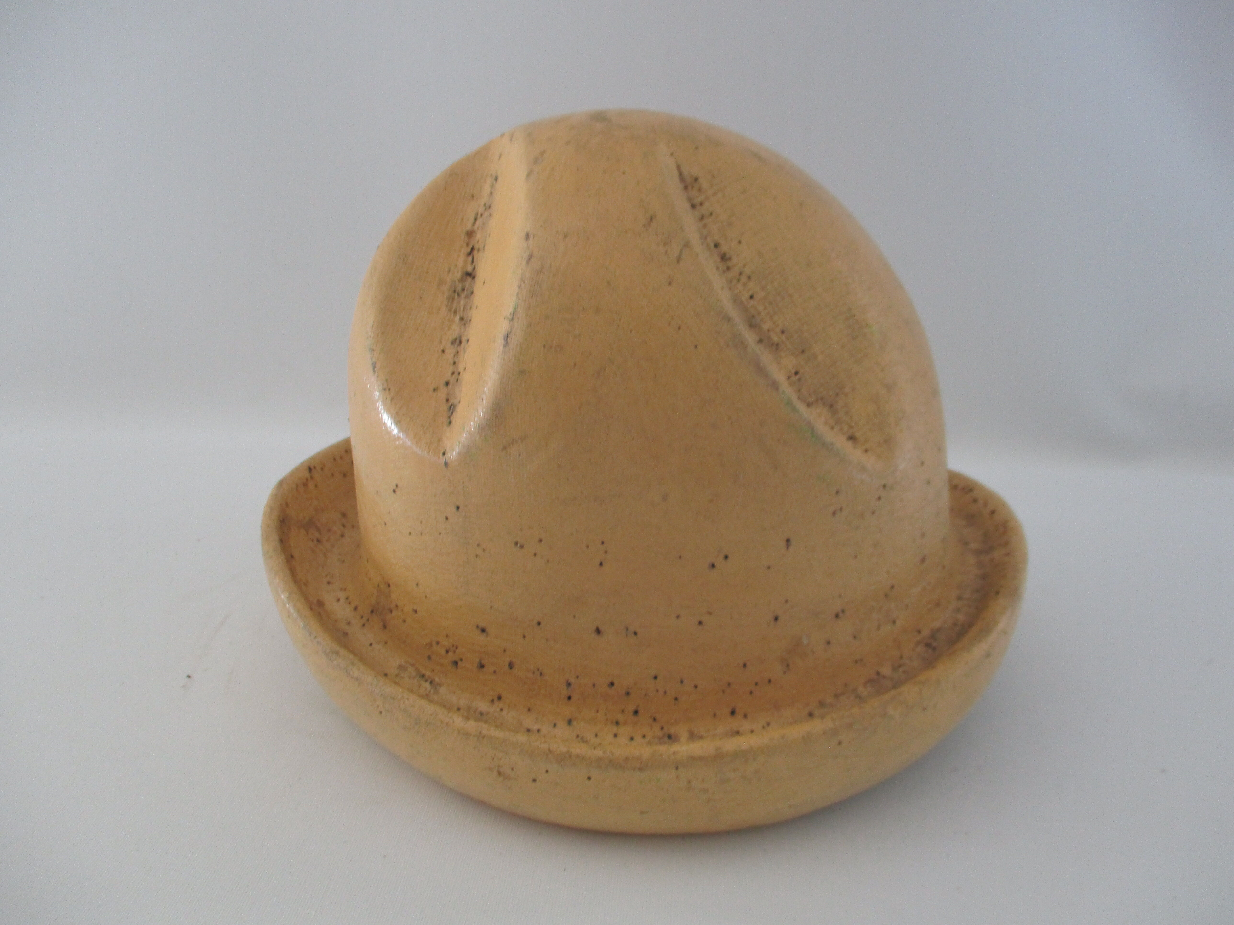Shape of pressed plaster hat with surface and textile fiber of yellowish color,